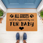 Funny pet lover doormat with the text All Guests Must Be Approved By Our Fur Baby, featuring black paw prints and a heart on a natural coir fiber welcome mat placed on a porch for dog owners and cat lovers seeking home decor.