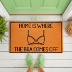 Funny doormat with the text Home Is Where The Bra Comes Off and a bra graphic, this humorous welcome mat is a stylish front porch decor piece for your home entrance, perfect for a housewarming or a fun gift for her on a white