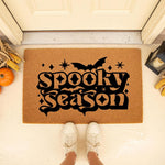 Spooky Season doormat featuring a black bat and star design on a natural coir welcome mat, perfect for fall porch decor, Halloween entryway rugs, and autumn home decorations placed outside a front door with pumpkins and corn