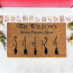Personalized family broom parking doormat for Halloween, featuring a natural coir welcome mat with custom names and witch broomstick illustrations, perfect for a spooky front porch entry decor during the fall autumn season.