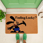 Lucky rabbit character doormat featuring a cartoon bunny in blue shorts with the text Feeling Lucky, this natural fiber welcome mat sits on a porch floor for a fun entryway decor look that greets guests with a playful and