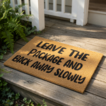 Funny Leave The Package And Back Away Slowly doormat, a natural coir fiber welcome mat with bold black text for your front porch, entry, or home decor, making a humorous statement for delivery drivers and guests at your front