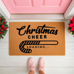 Christmas Cheer Loading doormat with a candy cane progress bar design on a natural coir fiber welcome mat, placed on a porch in front of a pink door for festive holiday home decor and seasonal entryway floor mat styling.