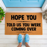 Funny welcome doormat with text Hope You Told Us You Were Coming Over, a natural coir fiber floor mat for front porch decor, featuring bold black lettering on a durable outdoor rug that makes a humorous housewarming gift for any