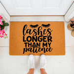 Funny Lashes Longer Than My Patience doormat featuring bold black typography and eyelash graphics on a natural fiber welcome mat, placed on a white porch floor with white sneakers standing in front of the entryway decor.