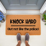 Funny Knock Hard doormat with humorous text for front porch decor, featuring a natural coir fiber welcome mat on a doorstep with gray sneakers standing on it, perfect for a sarcastic housewarming entry or home entrance rug.