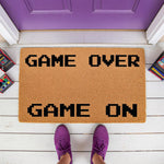 Game Over Game On doormat, a natural fiber welcome mat for gamers featuring pixelated text on a porch, perfect as a funny housewarming entry rug or front door decor for video game lovers who want a unique and stylish home
