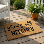 Funny shoe's off BITCHES doormat made of natural coir fiber, featuring bold black text on a textured brown background for a cheeky entryway welcome mat that serves as a humorous housewarming gift for a modern home or apartment