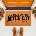 Funny cat welcome doormat featuring a black cat illustration and the text Please Wait For The Cat To Let You In, this natural coir fiber outdoor entry rug is a humorous home decor piece for any cat lover's front porch or entryway.