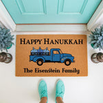 Personalized Hanukkah doormat featuring a blue truck carrying dreidels on a natural coir welcome mat, perfect for holiday porch decor.