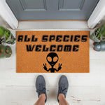 All Species Welcome alien doormat featuring a funny extraterrestrial graphic with peace signs, perfect for a sci-fi themed front porch decor, this durable coir welcome mat adds a quirky touch to any home entrance for space