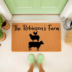 Personalized farm doormat featuring a cow, sheep, and chicken silhouette on natural coir fiber, perfect as a custom welcome mat for a farmhouse porch entrance with rustic decor and a light green front door background.