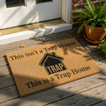 Funny Trap Home coir doormat with a house graphic and bold text that reads This isn't a Trap House This is a Trap Home, making this natural fiber welcome mat a humorous front porch decor choice for any modern or urban apartment