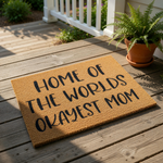 Funny Mom doormat featuring the text Home of the Worlds Okayest Mom in black lettering on a natural coir fiber welcome mat, a humorous front door rug for a mother that makes a great housewarming or birthday present for any home