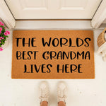 Worlds Best Grandma coir doormat for front porch entry, featuring natural fiber construction with black text that reads The Worlds Best Grandma Lives Here, a charming home decor welcome mat for a grandmother house entrance.