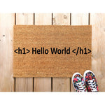 Hello World doormat for programmers, a natural coir fiber welcome mat with coding text printed on it, placed on a light wood porch floor next to a pair of floral sneakers, perfect for a tech-themed home entrance or office decor.
