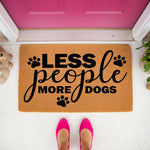 Less People More Dogs doormat featuring black paw prints on a natural coir fiber welcome mat, a funny dog lover front porch decor piece for pet owners who prefer canine company over human guests at their home entrance.