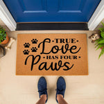 True Love Has Four Paws dog doormat featuring black paw prints on a natural coir fiber welcome mat, a stylish pet lover front porch decor piece that makes a fun housewarming entry rug for any dog owner or animal lover home