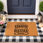 Simply Blessed coir doormat featuring black text on a natural fiber rug, displayed on a black and white buffalo check porch mat for a farmhouse entryway decor look that welcomes guests to your home with a stylish front door sign.