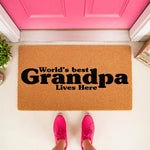 World's Best Grandpa coir doormat featuring bold black text on a natural fiber welcome mat, placed at a bright pink front door entrance for a fun home decor look that celebrates a beloved grandfather in a stylish, functional way.