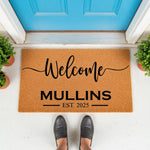 Personalized family name welcome doormat featuring a natural coir fiber texture, black script lettering, and established date, placed on a front porch entryway for a stylish home decor look that greets guests with a custom house
