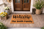 Personalized family name welcome doormat featuring custom text on a natural coir fiber mat, displayed on a rustic front porch with flowers and boots, perfect for a housewarming entrance decor or a custom outdoor floor mat for