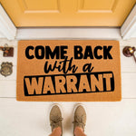 Funny Come Back With A Warrant doormat for front porch entry, featuring bold black text on a natural coir fiber welcome mat, perfect for a humorous home entrance decor style that keeps solicitors away from your front door step.
