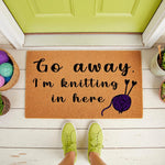 Knitting lover doormat with funny quote Go away I am knitting in here, featuring a purple yarn ball and needles design on a natural coir welcome mat for front porch decor, perfect for crafters and yarn enthusiasts at their home