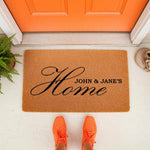 Personalized family name coir doormat featuring a script Home design on a natural fiber welcome mat, perfect for a front porch entryway, housewarming decor, or custom outdoor floor rug for a new home entrance with a bright orange