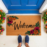 Floral Welcome Doormat with vibrant orange and magenta flowers on a natural coir fiber mat, featuring a stylish script font design for a front porch entryway, perfect for home decor and outdoor housewarming gifts for any new
