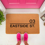 Personalized address doormat featuring custom street name and house number on natural coir fiber, perfect as a custom front porch welcome mat for new homeowners or housewarming decor in front of a bright pink door.