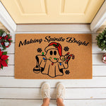 Christmas ghost doormat featuring a cute spirit wearing a Santa hat with colorful holiday lights, candy cane, and the text Making Spirits Bright on a natural coir welcome mat for festive front porch decor during the winter season.