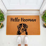 Bernese Mountain Dog welcome doormat featuring a cute dog portrait and the text Hello Hooman, this natural fiber coir entry rug is a funny pet lover front porch decor piece for dog owners placed outside a white front door.