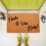 Hasta La Vista Baby doormat, a funny movie quote welcome mat for front porch decor, featuring bold black text on a natural coir fiber rug, perfect for sci-fi fans looking for a unique outdoor entrance mat for their home entryway.