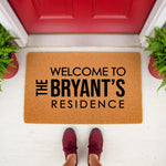 Personalized family name doormat featuring a natural coir texture, displayed on a front porch with a red door and potted ferns, making a stylish custom welcome mat for housewarming or new home decor for any residence entrance.