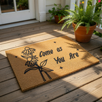Come as You Are floral doormat featuring a natural coir fiber texture with a black ink design of wildflowers and stars, making this a stylish welcome mat for your front porch entry or home decor entryway floor.