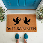 Dove welcome doormat with black bird design on natural coir fiber, featuring the German word for welcome in elegant lettering for a stylish front porch entrance, perfect for a housewarming gift or home decor entryway floor mat.