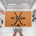 Personalized hockey family doormat featuring crossed hockey sticks and a puck design on natural coir fiber, perfect for a sports fan front porch entrance or a custom housewarming welcome mat for a hockey player home.