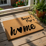 Personalized Nana and Pop's home doormat featuring a natural coir fiber texture with black script text and a heart icon, making a custom welcome mat for grandparents to place at their front door entrance for a cozy house look.