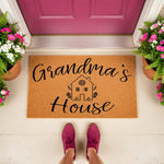 Grandma's House doormat featuring a cute home illustration on natural coir fiber, this personalized welcome mat for front porch decor makes a charming entryway rug for a family home, placed on a porch with pink flowers and