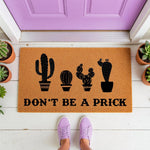 Funny cactus doormat with the text Don't Be A Prick, featuring a natural coir welcome mat design on a porch with potted plants, perfect for a humorous front door entrance or a quirky housewarming gift for plant lovers and