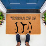 Waddle On In penguin doormat featuring three black and white birds on a natural coir fiber welcome mat, perfect for a fun front porch entrance or winter home decor that adds a playful touch to your entryway floor and house decor.