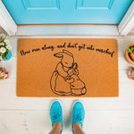 Rabbit family welcome doormat featuring a line art illustration of a mother bunny hugging her baby with the text Now run along and dont get into mischief, perfect for a spring porch decor or a cute housewarming entry rug.