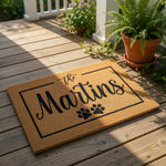 Personalized family name doormat with paw prints, a custom coir welcome mat for pet lovers featuring a rectangular border design, perfect for a front porch entrance or housewarming decor for dog and cat owners who love their pets.