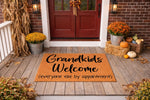 Grandkids Welcome doormat for front porch, a funny coir welcome mat with black text reading Grandkids Welcome everyone else by appointment, styled on a rustic wood porch with fall decor, pumpkins, and autumn mums for home entry.