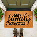 Family A Little World Created By Love doormat featuring a natural coir fiber texture, displayed on a front porch with a person standing on the welcome mat, perfect for a housewarming entry decor or a personalized home entrance