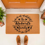 Personalized family name doormat featuring a black wreath design on a natural coir welcome mat, perfect for a front porch entryway.
