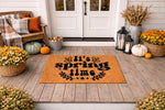 It's Spring Time coir doormat featuring bold black typography on a natural fiber welcome mat, displayed on a front porch with seasonal decor including pumpkins, flowers, and lanterns for a stylish outdoor entryway floor covering.
