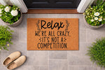 Funny doormat with the text Relax We're All Crazy It's Not A Competition, a natural coir fiber welcome mat for front porch decor that adds a humorous touch to your home entryway and makes a great housewarming gift for friends and