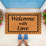 Welcome with Love coir doormat featuring a black heart border, placed on a porch in front of a blue door.
